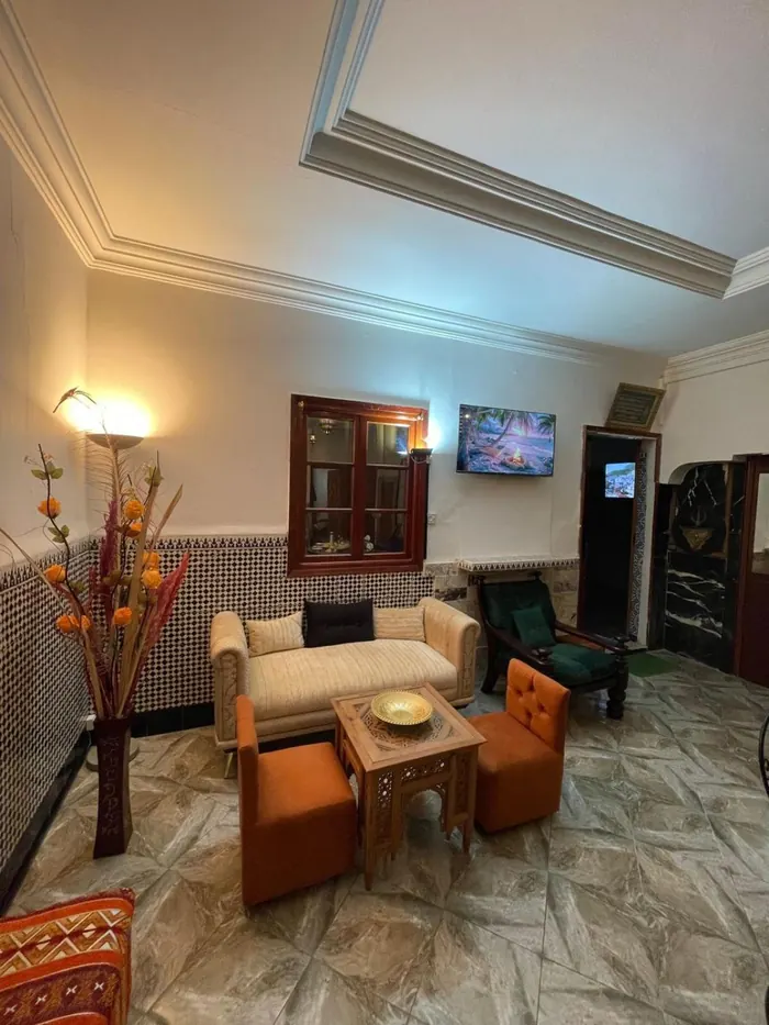 Un coin salon, canapé beige et fauteuils orange