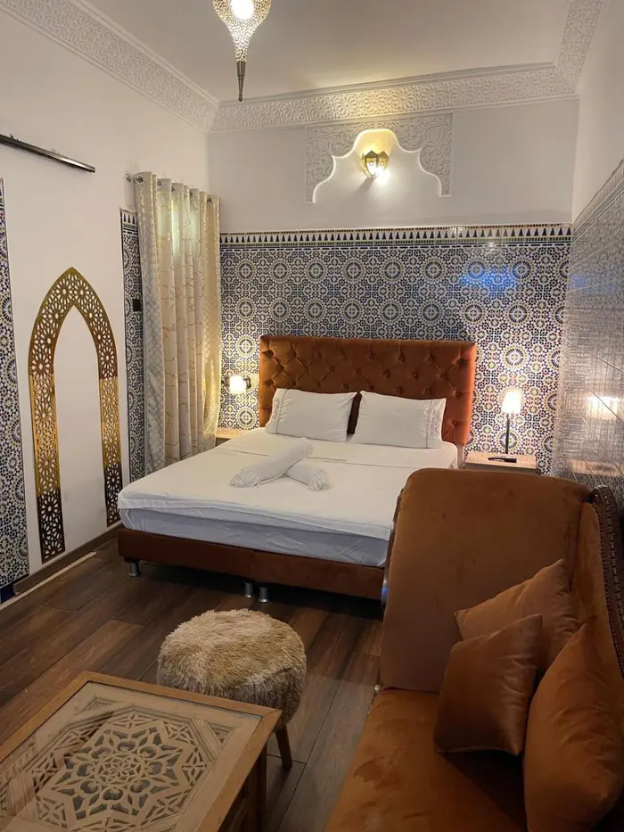 La chambre Deluxe, grand lit, canapé et arche dorée