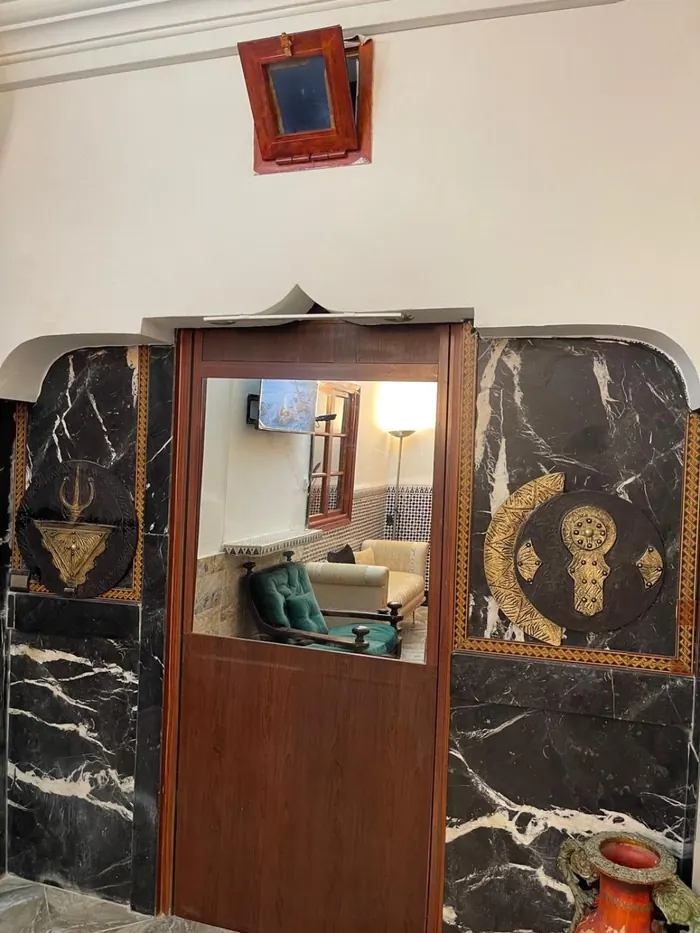 L’entrée en marbre noir, décorée de mains de Fatma en laiton