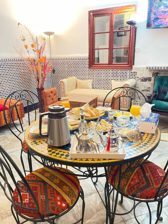 La table du petit-déjeuner dressée, théière et jus d’orange
